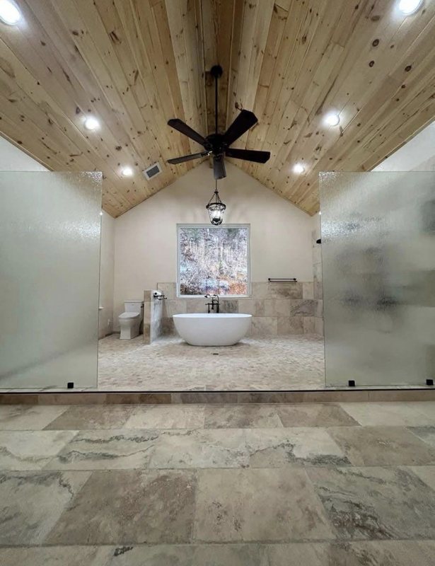 Bathroom with a cedar plank ceiling and fan, freestanding tub, large-format tile and a frosted glass window
