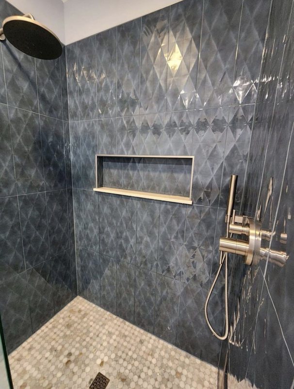 Walk-in shower with navy diamond-pattern tile, brushed brass rain head and fixtures, and a recessed niche