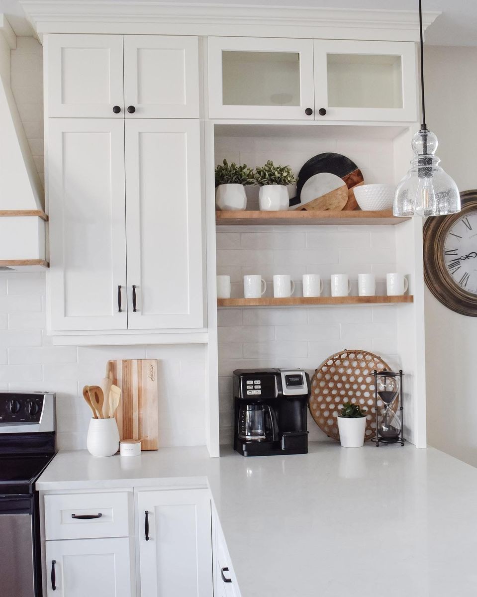 White kitchen corner with glass-front upper cabinets, floating wood shelves and a quartz countertop